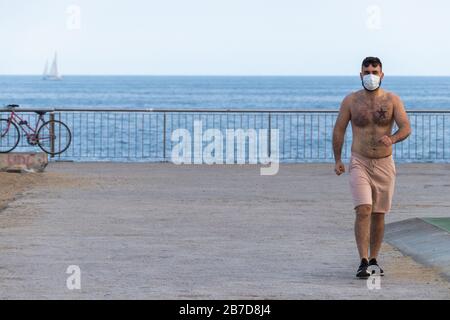 Barcelone, Espagne. 14 mars 2020. Homme marchant sur le bord de mer de Barcelone avec un masque de protection crédit: Dino Geromella/Alay Live News Banque D'Images