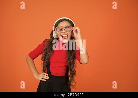 Piste froide. Fille avec lunettes arrière-plan orange. Événement et divertissement. Fille de fête. Accessoire de fête. Amuse-toi bien. Liste de lecture pour la fête. Concept de musique. Enfant porter des lunettes. Magasin de mode de lunettes. Banque D'Images