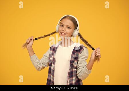Avec la technologie sans fil. Petit enfant à écouter de la musique sans fil moderne d'écouteurs. Happy little girl wearing headphones moderne. Cute kid bénéficiant d'un son stéréo. C'est la liberté sans fil. Banque D'Images