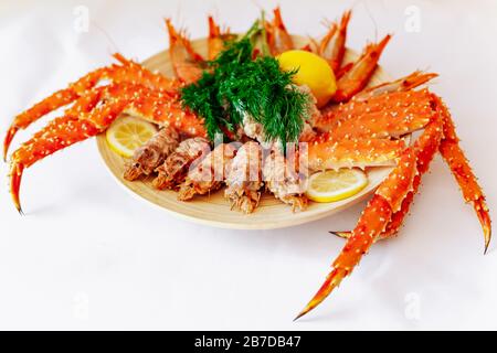 Le crabe royal rouge et les crevettes sur une plaque avec du citron et l'aneth. Fond blanc Banque D'Images