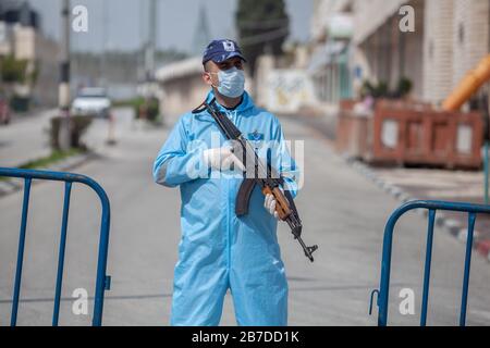 Bethléem. 15 mars 2020. Le 15 mars 2020, un policier palestinien portant des engins de protection est en garde près d'une zone en quarantaine dans la ville de Bethléem, en Cisjordanie. La Palestine a signalé samedi trois nouveaux cas de COVID-19, portant le nombre total de cas confirmés au pays à 38. Crédit: Luay Sababa/Xinhua/Alay Live News Banque D'Images