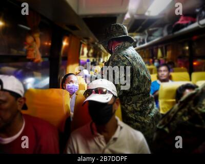 Philippines. 15 mars 2020. Philippines. 15 mars 2020. (3/15/2020) un policier inspecte la température d'une femme en déplacement à bord d'un autobus public. Des mesures de ce type sont prises pour veiller à ce que les gens qui vont dans la région de la capitale nationale et qui sortent de celle-ci n'aient pas les symptômes de Covid-19. Crédit: Sipa Usa/Alay Live News Banque D'Images