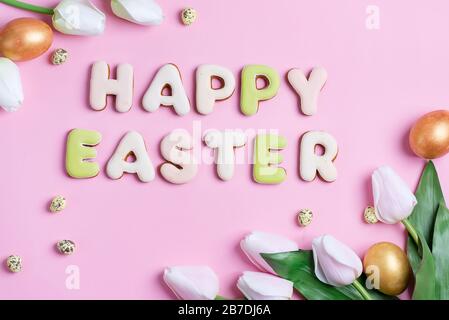 Félicitations bonne carte de Pâques de poulet peint à la main et des œufs de caille, fleurs de tulipes et texte de biscuits faits maison de lettres cuites sur un bac rose Banque D'Images