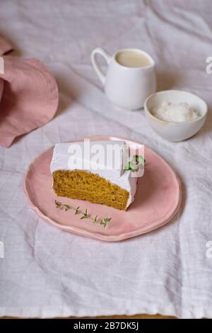 Tranche de gâteau aux carottes végétaliennes avec glaçage à la crème de noix de coco servi sur une plaque rose Banque D'Images
