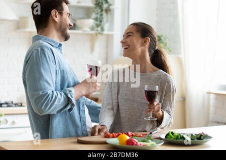 Jeune couple aimant s'amuser dans la cuisine, boire du vin Banque D'Images