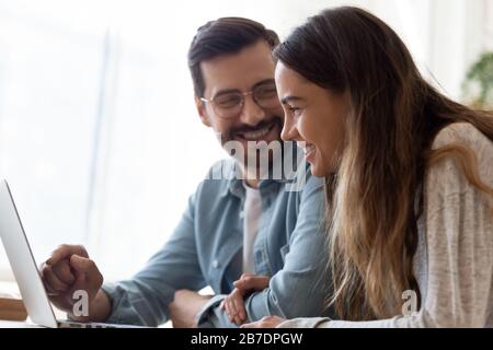 Heureux couple aimant utilisant l'ordinateur portable ensemble, tenant les mains Banque D'Images