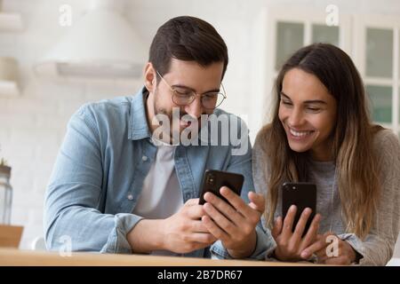 Un jeune couple heureux utilisant des smartphones ensemble, s'amuser Banque D'Images