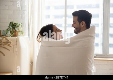 Un couple heureux et affectueux enveloppé dans une couverture chaude qui épouse la forme Banque D'Images
