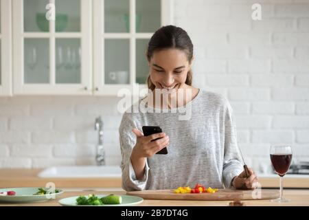 Femme souriante avec smartphone, salade de cuisine, collation saine Banque D'Images