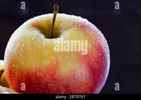 Pomme avec des gouttes d'eau sur fond sombre. Banque D'Images