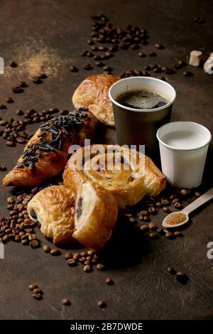 Variété de pains à base de raisins secs et de chocolat, croissant avec tasses de café americano et de lait, grains de café, bois recyclé Banque D'Images