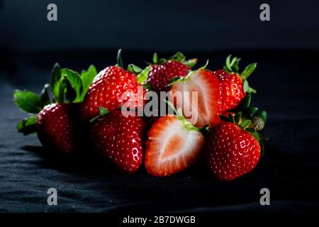 Belles fraises rouges avec fond noir et pluie légère Banque D'Images