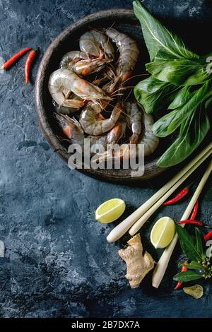 Crevettes à la crevette crue aux nouilles asiatiques, au lait de noix de coco et aux légumes. Ingrédients pour la cuisine du dîner asiatique ou soupe thaïlandaise tom yum. Fond en béton foncé. Banque D'Images