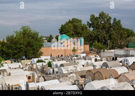 Ancien cimetière au mausolée bleu couté de Madari Khan en arrière-plan, à Kokand, en Ouzbékistan. Banque D'Images