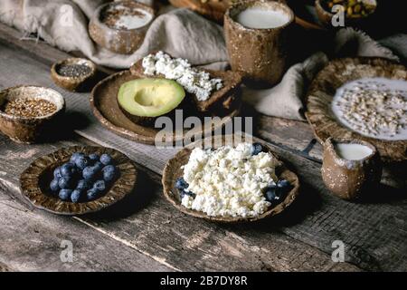 Petit déjeuner sain. Assortiment de plats de petit déjeuner composé de blé, yaourt, kéfir, fromage cottage, avocat, pain de seigle, graines, noix et baies i Banque D'Images