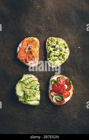 Variété de sandwichs pour le petit-déjeuner, en-cas, hors-d'œuvre - purée d'avocat, mozzarella, tomates, basilic, fromage à la crème, saumon fumé, oignon rouge, concombre Banque D'Images