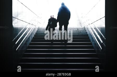 père conduit sa fille de ténèbres à la lumière sur les escaliers d'un tunnel souterrain Banque D'Images