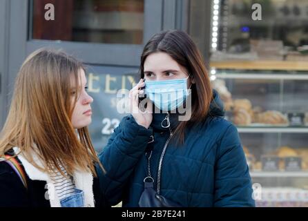 Kiev, Kiev, Ukraine. 13 mars 2020. Une jeune femme portant un masque protecteur comme mesure préventive contre le virus corona utilise un téléphone mobile dans la rue. Le gouvernement ukrainien interdit temporairement aux étrangers d'entrer en Ukraine et met fin aux services internationaux réguliers de transport de passagers à partir du 17 mars 2020, pour lutter contre la propagation de nouveaux coronavirus en Ukraine. Crédit: Pavlo Gonchar/Sopa Images/Zuma Wire/Alay Live News Banque D'Images