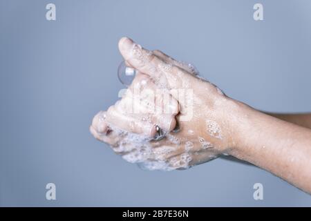 lavage des mains avec de la mousse de savon sur fond bleu, concept de prévention des virus et des bactéries, photo horizontale, espace de copie pour le texte Banque D'Images