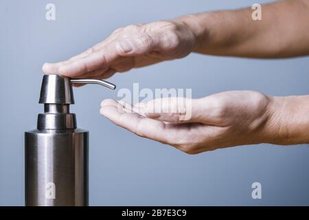 mains mettant du savon avec un distributeur sur fond bleu, hygiène et soin de la peau concept, photo horizontale avec espace de copie pour le texte Banque D'Images