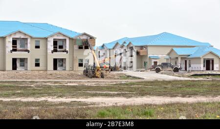 Reconstruction des appartements Salt Grass Landing. Les travailleurs qui installent la garniture de vitre, surélevés avec l'élévateur de matériau Caterpillar. Banque D'Images