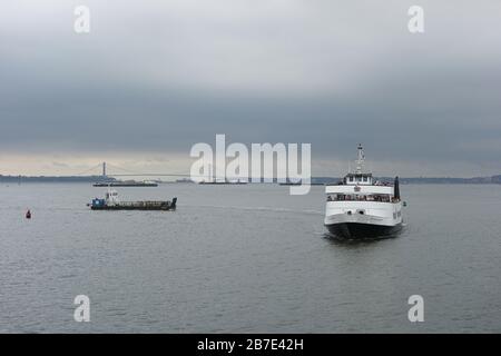 Bateau de croisière de la Statue de la liberté V et divers autres navires sur le fleuve Hudson en journée nuageux avec le pont Verrazzano Narrows en arrière-plan Banque D'Images
