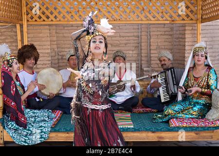 Musiciens locaux jouant et femme ouzbek en costumes traditionnels dansant à Khiva, Ouzbékistan Banque D'Images