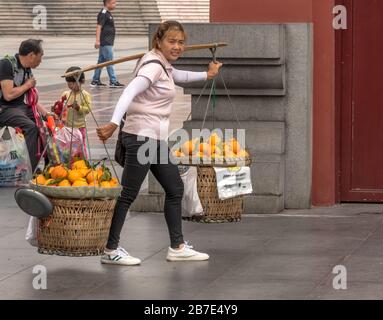 Vendeur de fruits transportant d'énormes paniers de fruits sur un poteau ou un étrier de transport traditionnel, Chongqing Banque D'Images