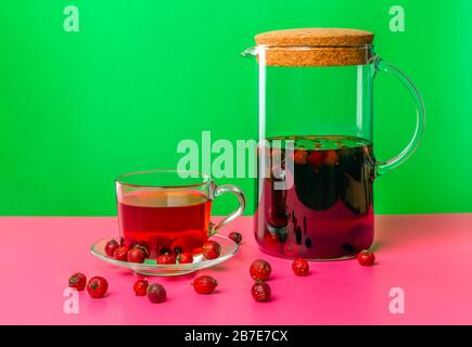 Une tasse avec une infusion de baies de rosehip séchées avec une fleur sur une table noire avec réflexion. Banque D'Images