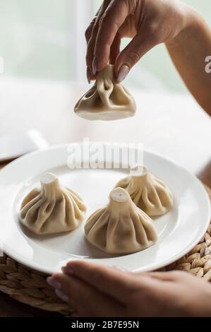 Kinkali traditionnel géorgien sur plaque jaune. Un Khinkali a tenu dans la main de la femme. Un restaurant. Banque D'Images