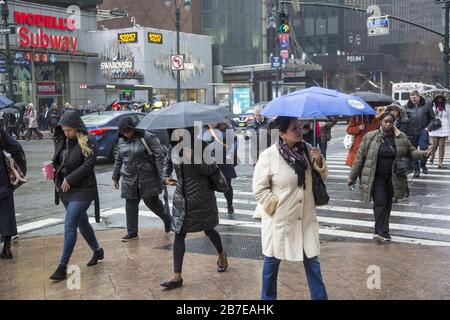 La pluie légère accueille les gens qui viennent travailler à Manhattan pendant l'heure de pointe du matin au 34ème rue et 7ème Avenue à côté d'une grande station de métro et de la gare de Penn. NEW YORK. Banque D'Images