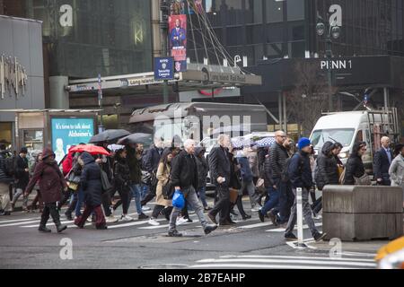 La pluie légère accueille les gens qui viennent travailler à Manhattan pendant l'heure de pointe du matin au 34ème rue et 7ème Avenue à côté d'une grande station de métro et de la gare de Penn. NEW YORK. Banque D'Images