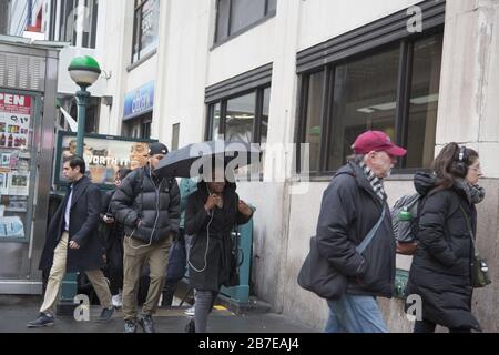 La pluie légère accueille les gens qui viennent travailler à Manhattan pendant l'heure de pointe du matin au 34ème rue et 7ème Avenue à côté d'une grande station de métro et de la gare de Penn. NEW YORK. Banque D'Images