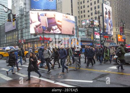 La pluie légère accueille les gens qui viennent travailler à Manhattan pendant l'heure de pointe du matin au 34ème rue et 7ème Avenue à côté d'une grande station de métro et de la gare de Penn. NEW YORK. Banque D'Images