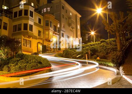 Twisted Lombard Street la nuit avec des sentiers de feux de voiture à San Francisco. Les sentiers de lumière blanche et rouge se recourent autour du coin. Banque D'Images