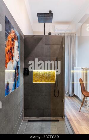 Budapest, Hongrie - 16 février 2020: Douche en verre avec carreaux gris en pierre de granit et peinture féminine, à l'intérieur de la chambre. Banque D'Images