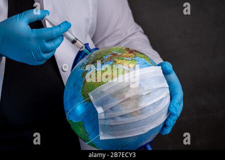 Médecin vaccinant la terre à cause du coronavirus avec des gants médicaux bleus Banque D'Images