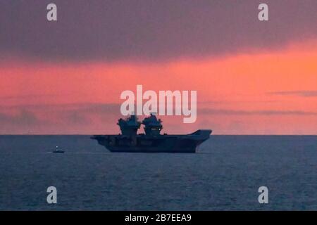Lullworth, Dorset, Royaume-Uni. 15 mars 2020. Météo britannique. Britains le plus récent porte-avions HMS Prince of Wales ancré dans la baie de Weymouth au coucher du soleil. Crédit photo : Graham Hunt/Alay Live News Banque D'Images