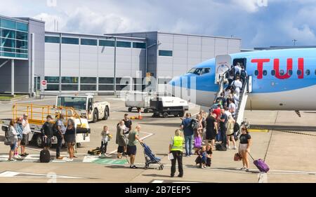 BRISTOL, ANGLETERRE - AOÛT 2019: Groupe de passagers faisant la queue pour monter à bord par la porte avant d'un avion de vacances TUI Boeing 737 à l'aéroport de Bristol. Banque D'Images