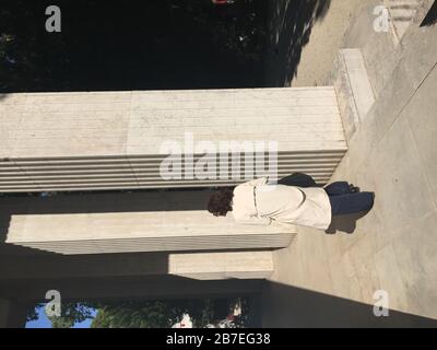 Photo verticale d'une femme marchant à côté de colonnes en béton Banque D'Images