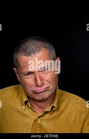 Portrait d'un homme avec des émotions grotesque sur fond noir Banque D'Images