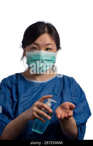 Une jeune femme médecin asiatique portant un masque de protection vert à l'aide d'un désinfectant pour les mains sur fond blanc Banque D'Images