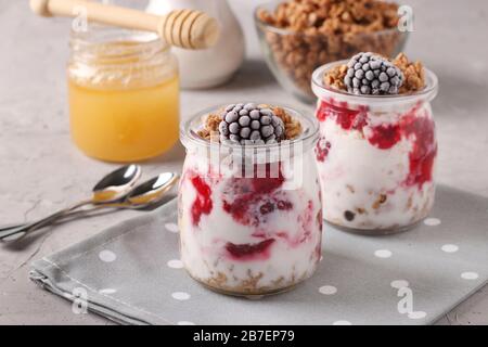 Muesli au miel croustillant de granola avec baies noires surgelées, banane, fromage cottage et yaourt naturel, un délicieux petit déjeuner sain, situé dans le verre Banque D'Images