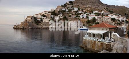 Panorama avec une terrasse de restaurant grec donnant sur la mer Égée et l'entrée du port d'Hydra, Grèce Banque D'Images