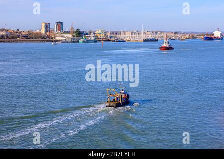 Un petit bateau de pêche traditionnel en mer retournant au port de Portsmouth et un remorqueur près du littoral de Gosport, Portsmouth, Hampshire, côte sud de l'Angleterre Banque D'Images