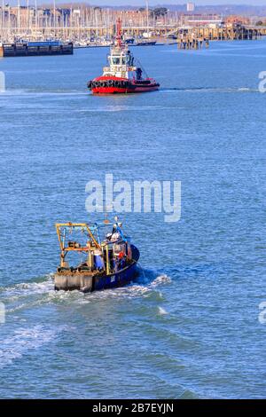 Un petit bateau de pêche traditionnel en mer retournant au port de Portsmouth et un remorqueur près du littoral de Gosport, Portsmouth, Hampshire, côte sud de l'Angleterre Banque D'Images