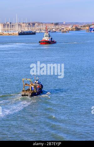 Un petit bateau de pêche traditionnel en mer retournant au port de Portsmouth et un remorqueur près du littoral de Gosport, Portsmouth, Hampshire, côte sud de l'Angleterre Banque D'Images