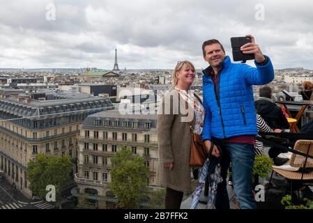 Deux personnes qui prennent un selfie ensemble du toit des Galeries Lafayette avec la Tour Eiffel en arrière-plan, Paris, France, Europe Banque D'Images