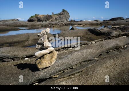 Pierres empilées dans un tas de Cairn sur un affleurement rocheux le long d'un littoral du Pacifique, île Biri, Philippines Banque D'Images