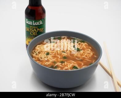 studio shot bol de nouilles ramen oignons verts bâtonnets de hache et bouteille d'huile de sésame fond blanc Banque D'Images